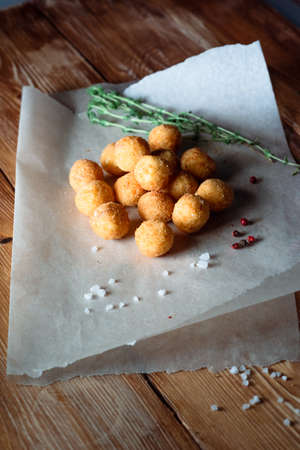 Grilled cheese balls on a wooden surface among spices and salt. Concept of beer snacks and fast food
