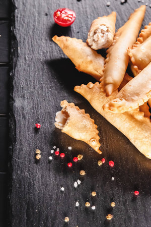 Fried fish in batter among spices and sauces on a black stone tray. Fast and ready meal conceptの写真素材
