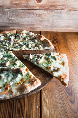 Appetizing pizza on a wooden table surrounded by herbs and spices. The concept of delicious food,...