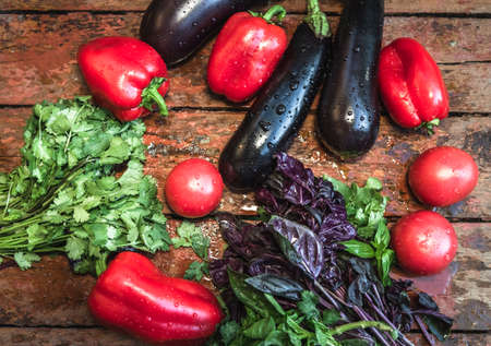Farm tomatoes, eggplants and greens lie on a wooden surface. Concept of biological, bio products, bio ecology, grown by yourself, vegetariansの写真素材
