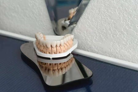 An artificial jaw with veneers and crowns, stands on a surgical glass in a stolmatologic office....