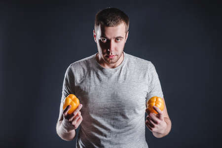 Portrait of an attractive man who tosses vegetables in the studio on a gray background. The concept of proper nutritionの写真素材