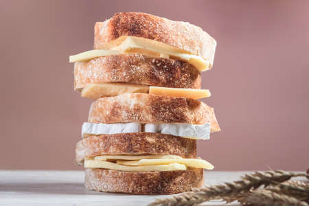 Sliced rustic bread and cheese on a white wooden board. Healthy food and farming conceptの写真素材