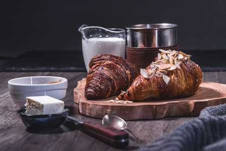 Croissants, milk and coffee on a wooden table in a low key. The concept of traditional breakfasts and delicious foodの写真素材