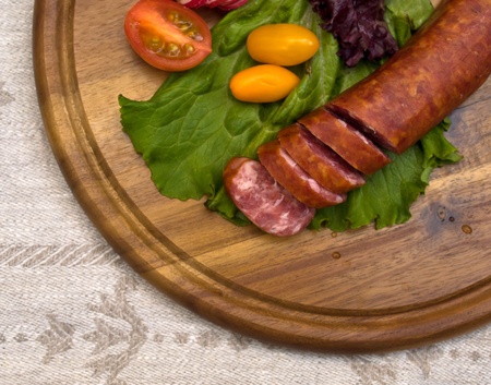 Breakfast close-up. Slices of sausage on the wooden plate with knife