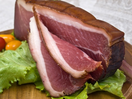 Breakfast close-up. Slices of bacon on the wooden plate with knifeの写真素材