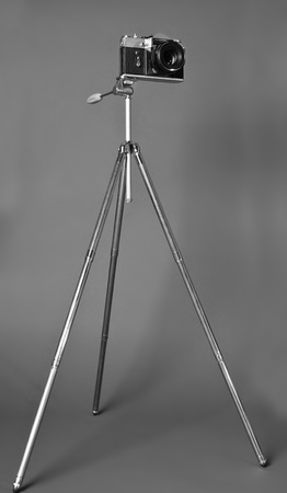 Old film camera and retro steel tripod on grey backgroundの写真素材