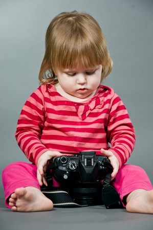 Cute little baby with digital photo camera on gray backgroundの写真素材