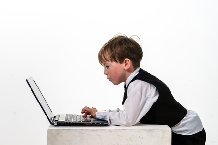 Freckled red-hair little boy with laptop. Isolated on white background.