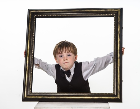 Freckled red-hair little boy with big picture frame. Isolated on white background.の写真素材