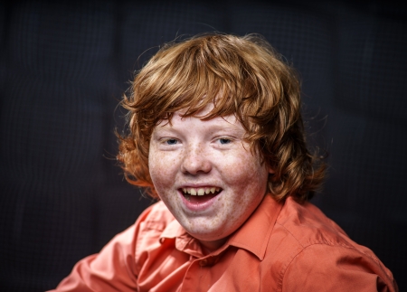 Freckled red-hair boy posing on dark background. Emotions.の写真素材