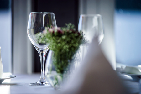 Fine restaurant dinner table setting by wineglass and napkinの写真素材