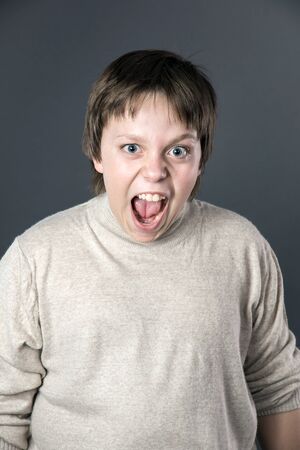 Teenage boy emotion portrait. Isolated on grey background.