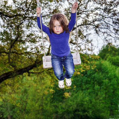 Cute little girl swinging on seesaw to the skyの写真素材