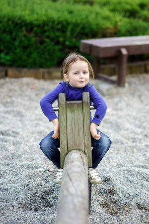 Cute little girl swinging on seesaw to the skyの写真素材