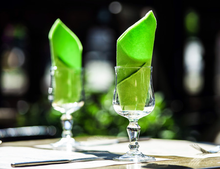 Wineglasses and napkins ready for dinner in cafeの写真素材
