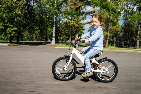Cute little girl riding fast by bicycle in public parkの写真素材