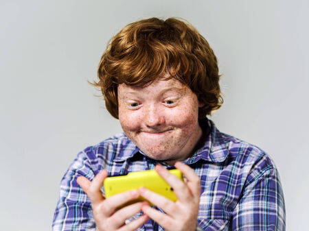 Comic freckled red-haired boy with mobile telephone