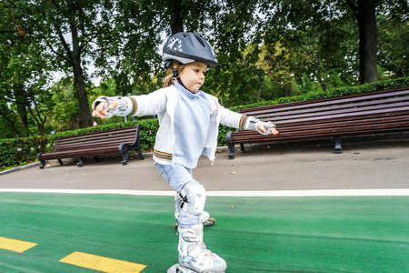 Cute little girl learning rollerskating in public parkの写真素材