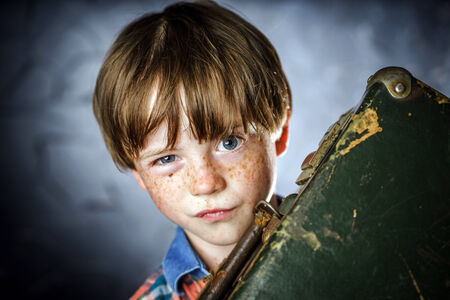Emotional red-haired boy with retro vintage suitcaseの写真素材