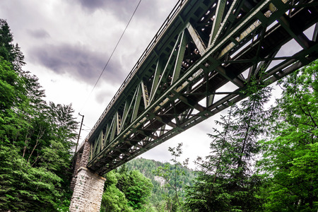 High railway bridge over the mountains river, stormy weatherのeditorial素材