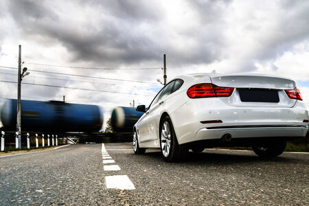 Luxury white car waiting for train  at the railway crossingのeditorial素材