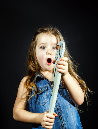 Cute little girl with gas spanner in her hands ready to professional constructing workの写真素材