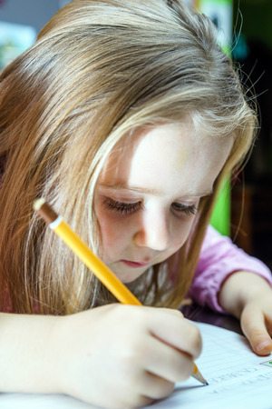 Cute little girl studing to speaking and writing letters at home lesson with her motherの写真素材