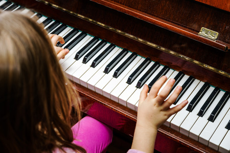 Little girl studing to play the piano at home