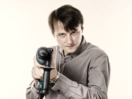 Young man with drilling machine in his hands ready to professional constructing workの写真素材