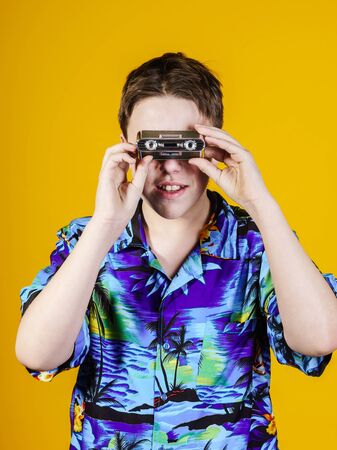 Teenage boy with opera binocular close-up portrait isolated on yellow background