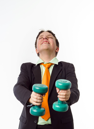 Teenage boy dressed in office suit doing sport exercises with dumbbellsの写真素材