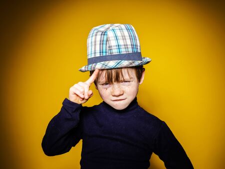 Red-haired expressive preschooler boy close-up emotional portrait, isolated on yellow