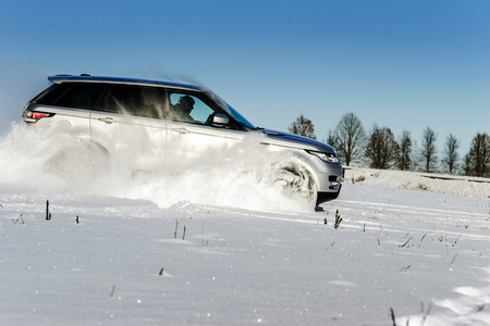 Powerful 4x4 offroader car running on snow field winter day, transport conceptの写真素材