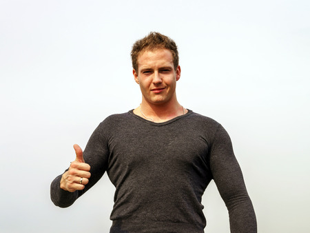 Attractive young fashion man smiling to the camera while showing the thumbs up gesture