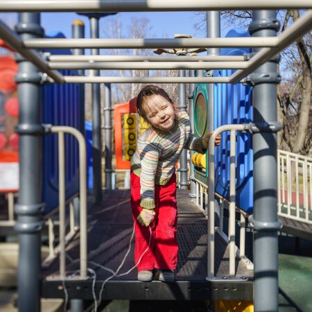 Cute little girl playing on child playground, spring sunny dayの写真素材