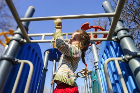 Cute little girl playing on child playground, spring sunny day