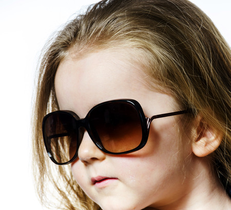 Cute little girl posing in mother's sunglasses, childhood concept, isolated on whiteの写真素材