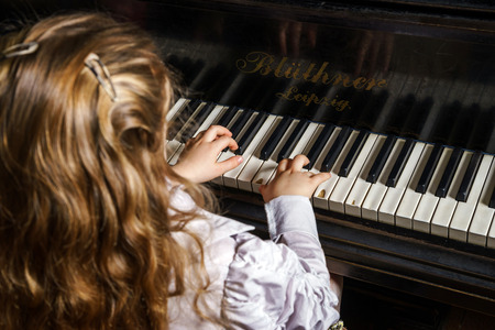 Cute little girl playing grand piano in music school, childhood conceptの写真素材