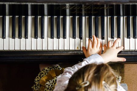 Cute little girl playing grand piano in music school, childhood conceptの写真素材