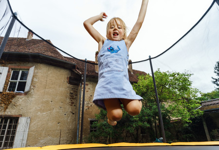 Cute preschooler girl jumping on trampoline, childhood conceptの写真素材