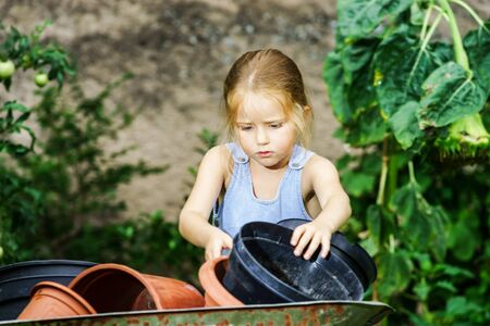 Cute little girl helping her mother in the backyard with heavy wheelbarrowの写真素材
