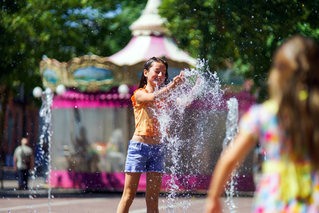 Two sisters playing with fountain splash on the central street of Selestatの写真素材