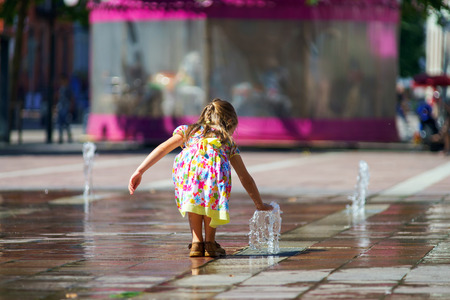 Cute little girl playing with fountain splash on the central street of Selestatの写真素材