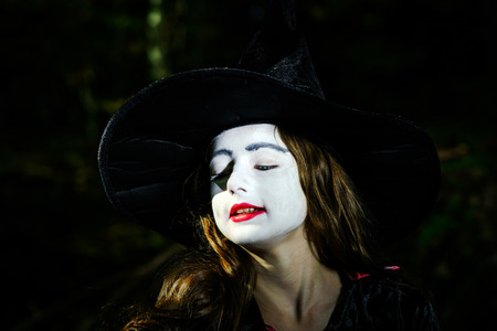 Girl in the forest dressed Halloween witch costume, holiday concept