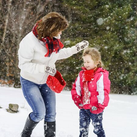 Mother playing with her daughter in snow on ski resort