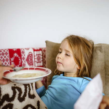 Mother feeding taken ill daughter by semolina, spoonfeedingの写真素材