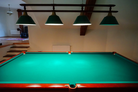Green billiard table in private apartment with lamps over it