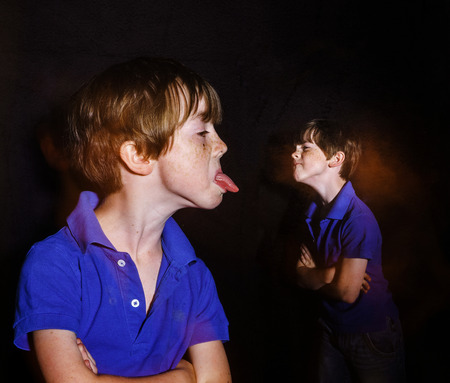 Double-exposed portrait of red-haired freckled boy, dark background