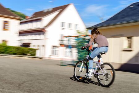 Teenage girl bicycling in roller boots. Quickly moving.の写真素材
